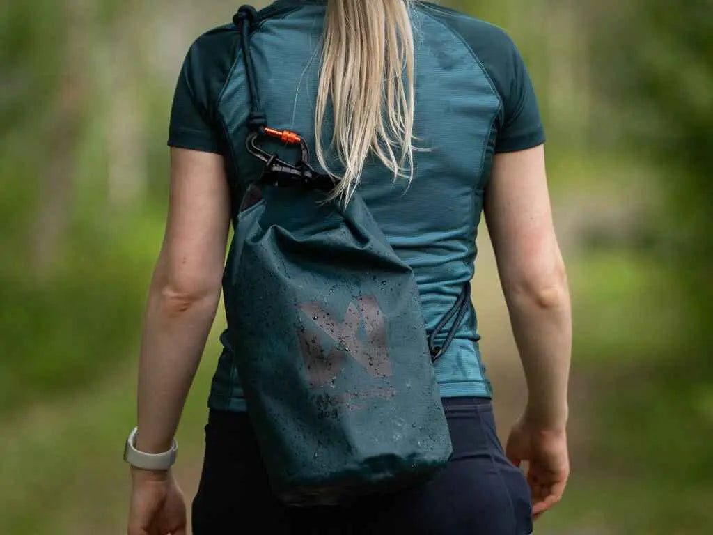 Person wearing a green drawstring bag with a brand logo outdoors