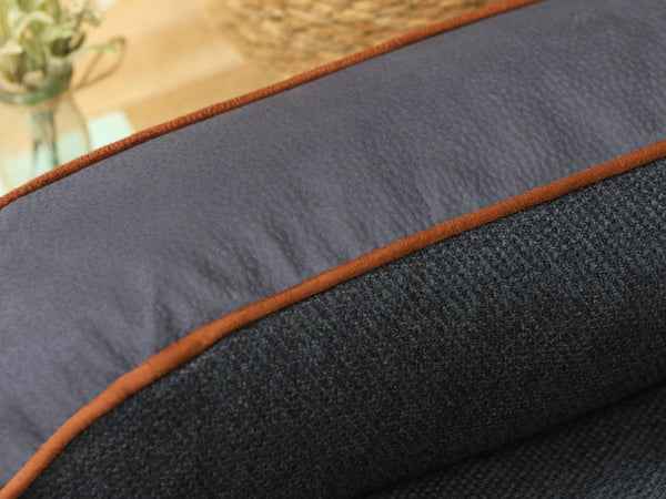 George Barclay Holbury Dog Sofa Bed - Moonlight. Close-up of the blue and grey fabric with brown piping on a blurred background